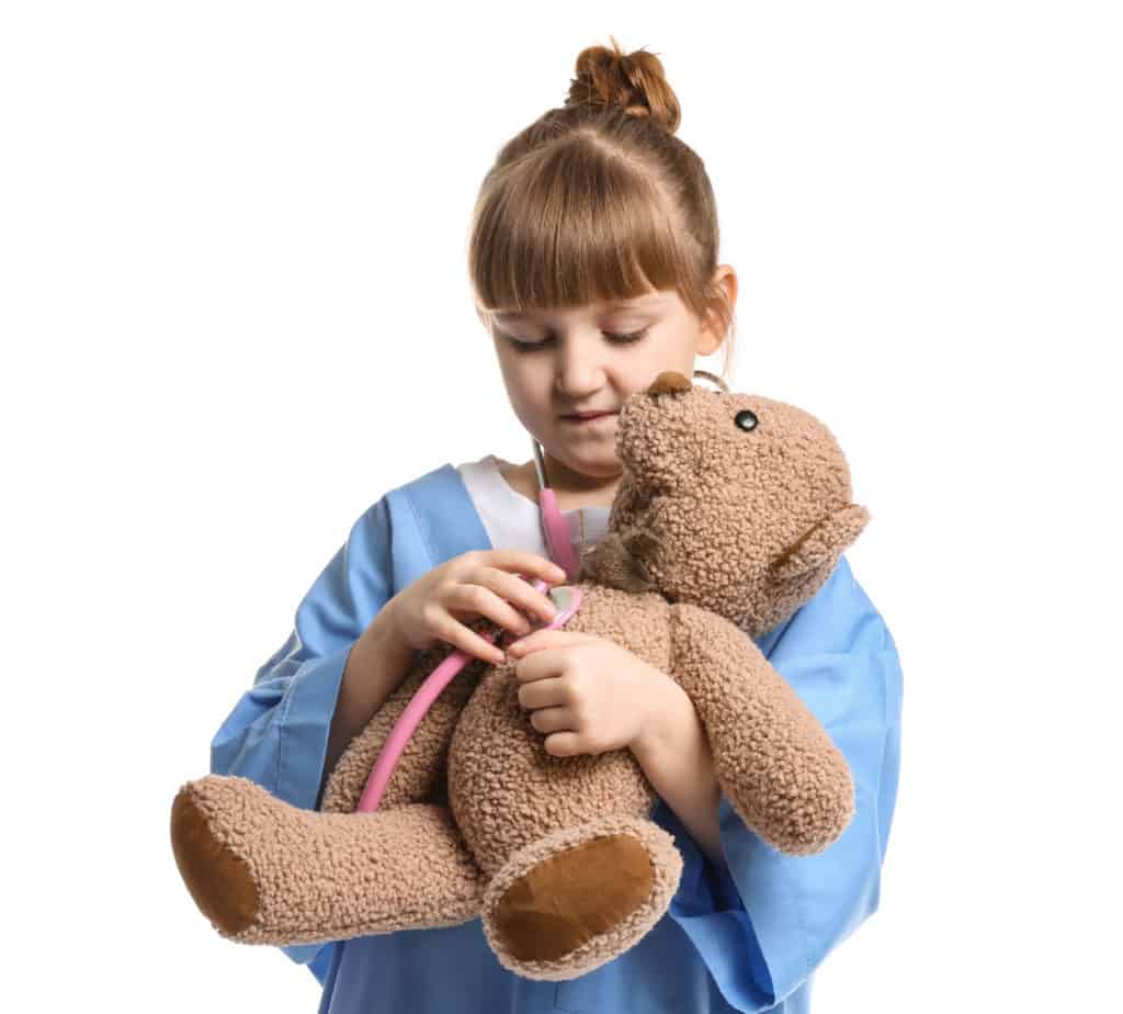 Girl in hospital scrubs holding a teddy bear