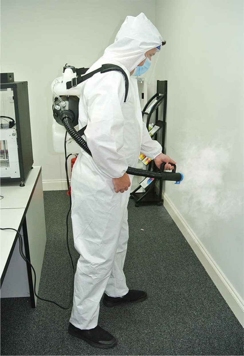 Man in overalls spraying DRYMIST disinfectant